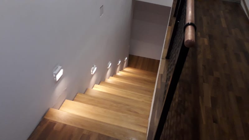 Nyitott, vasvázas lépcső, tölgyfa lépcsőlapokkal, rezgéscsillapítással.