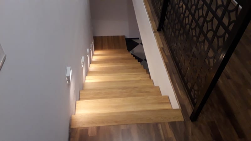 Nyitott, vasvázas lépcső, tölgyfa lépcsőlapokkal, rezgéscsillapítással.