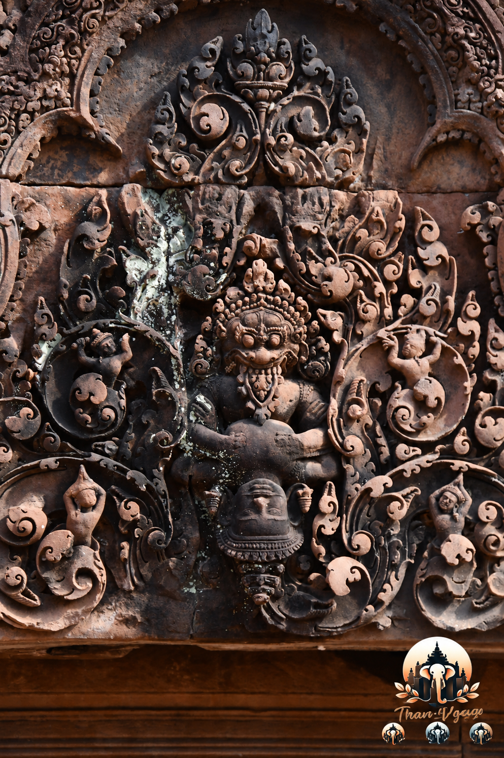 Détail d’un linteau de Banteay Srei : au-dessus, un kala ou kirtimukha, figure monstrueuse protectrice, domine une composition foisonnante de rinceaux et de personnages mythologiques. Ces décors ne sont pas de simples ornements : ils protègent symboliquement le seuil du sanctuaire et rappellent la richesse de l’univers sacré khmer.