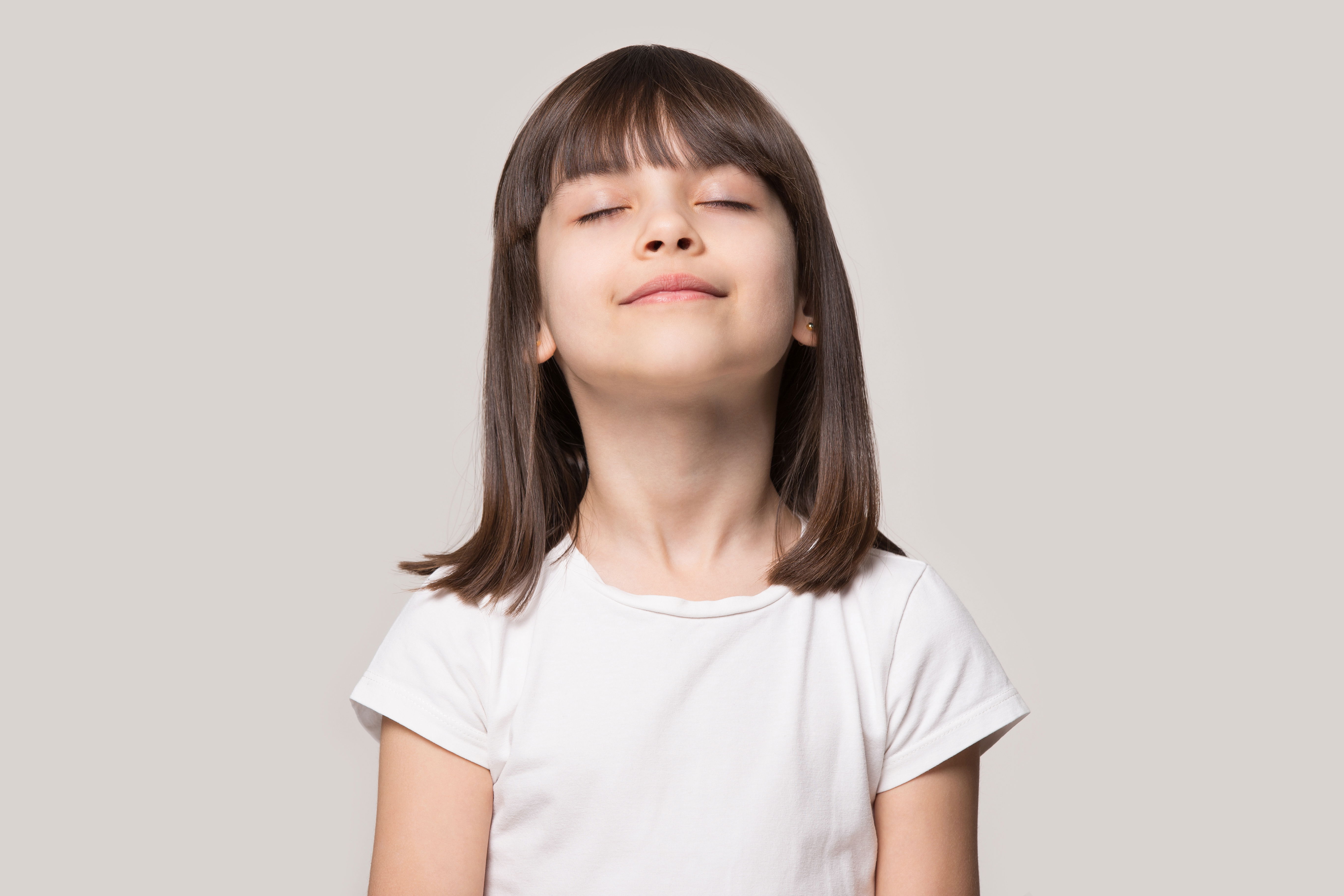 Petite fille debout, les yeux fermés, pratiquant la méditation, symbolisant la tranquillité et l’équilibre émotionnel dans le cadre de la sophrologie.