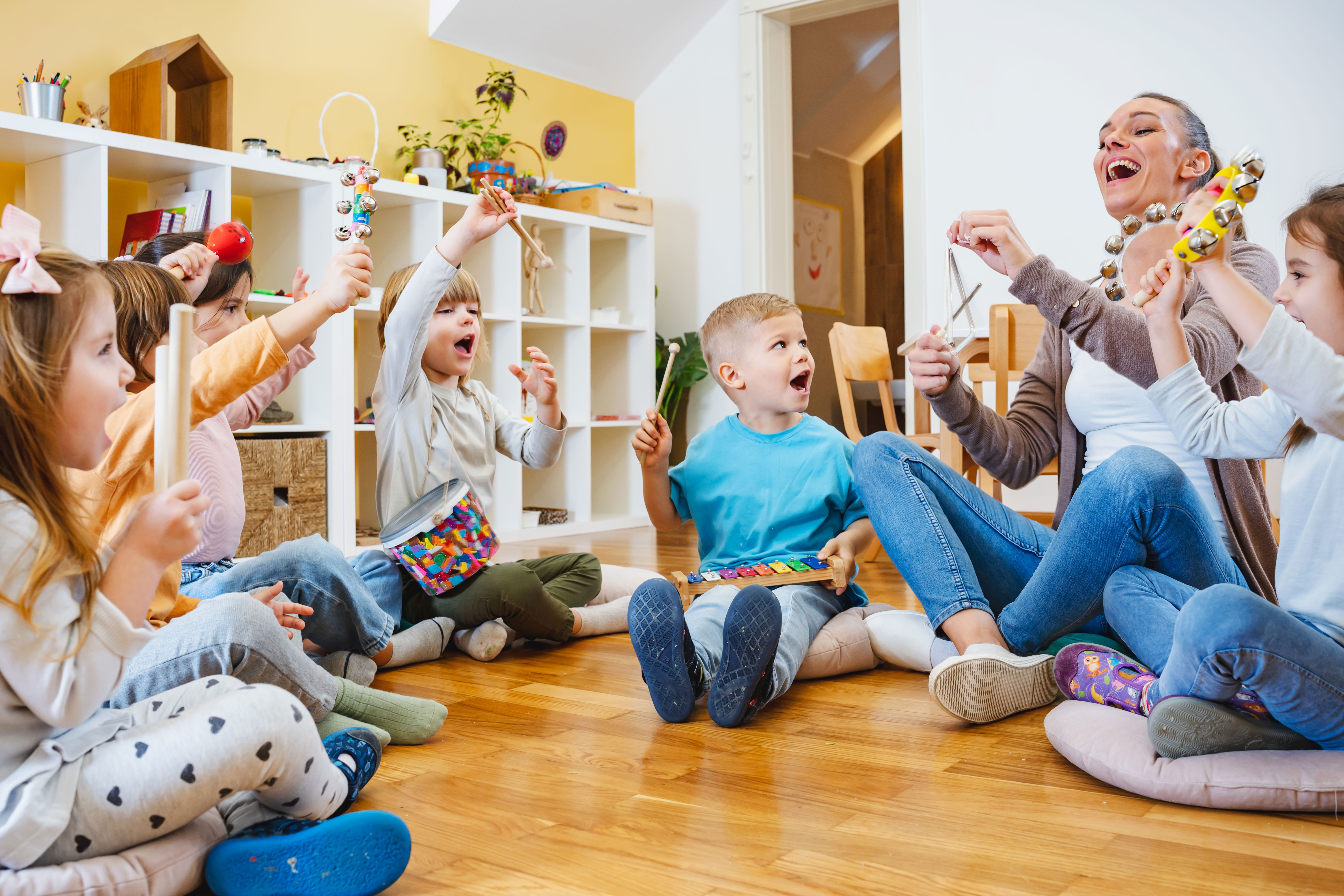 Groupe de jeunes enfants de maternelle, assis avec une sophrologue, pratiquant des jeux ludiques, illustrant l’approche ludique de la sophrologie adaptée aux enfants. 