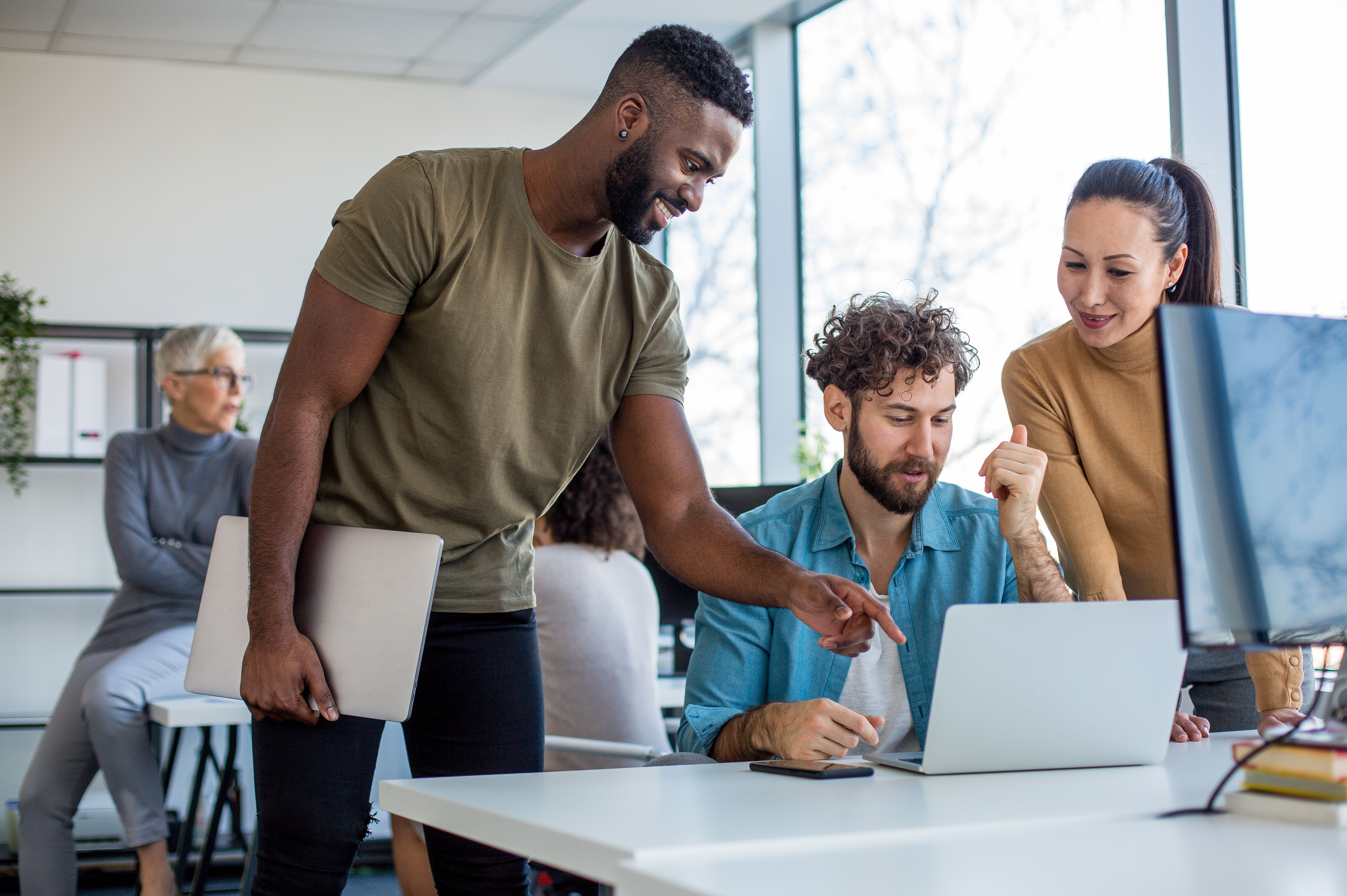 Collaborateurs travaillant ensemble devant un ordinateur pour renforcer la cohésion et l’esprit d’équipe.