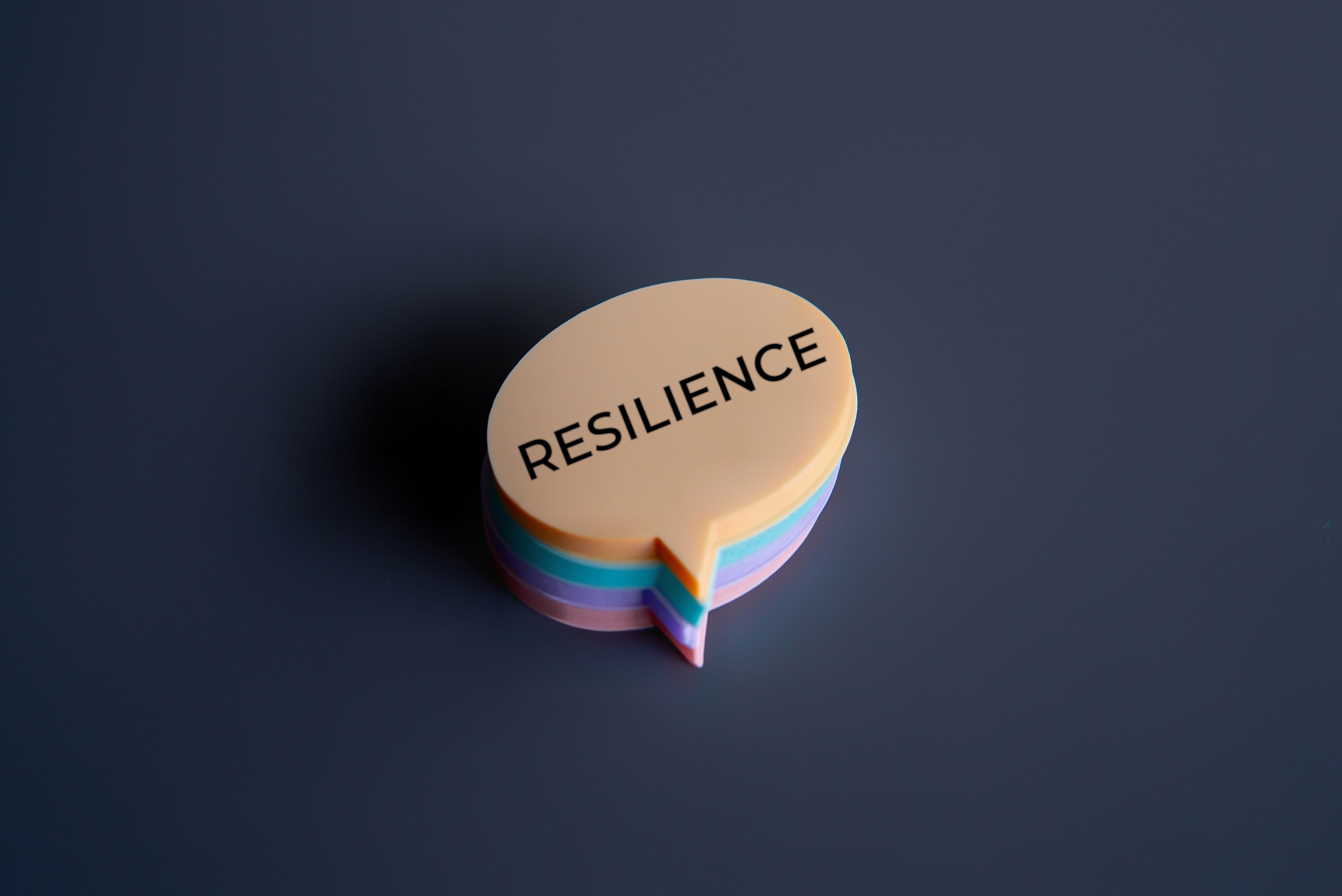 Le mot « résilience » écrit sur une petite pile de post-it multicolore, en forme de bulle d’expression.