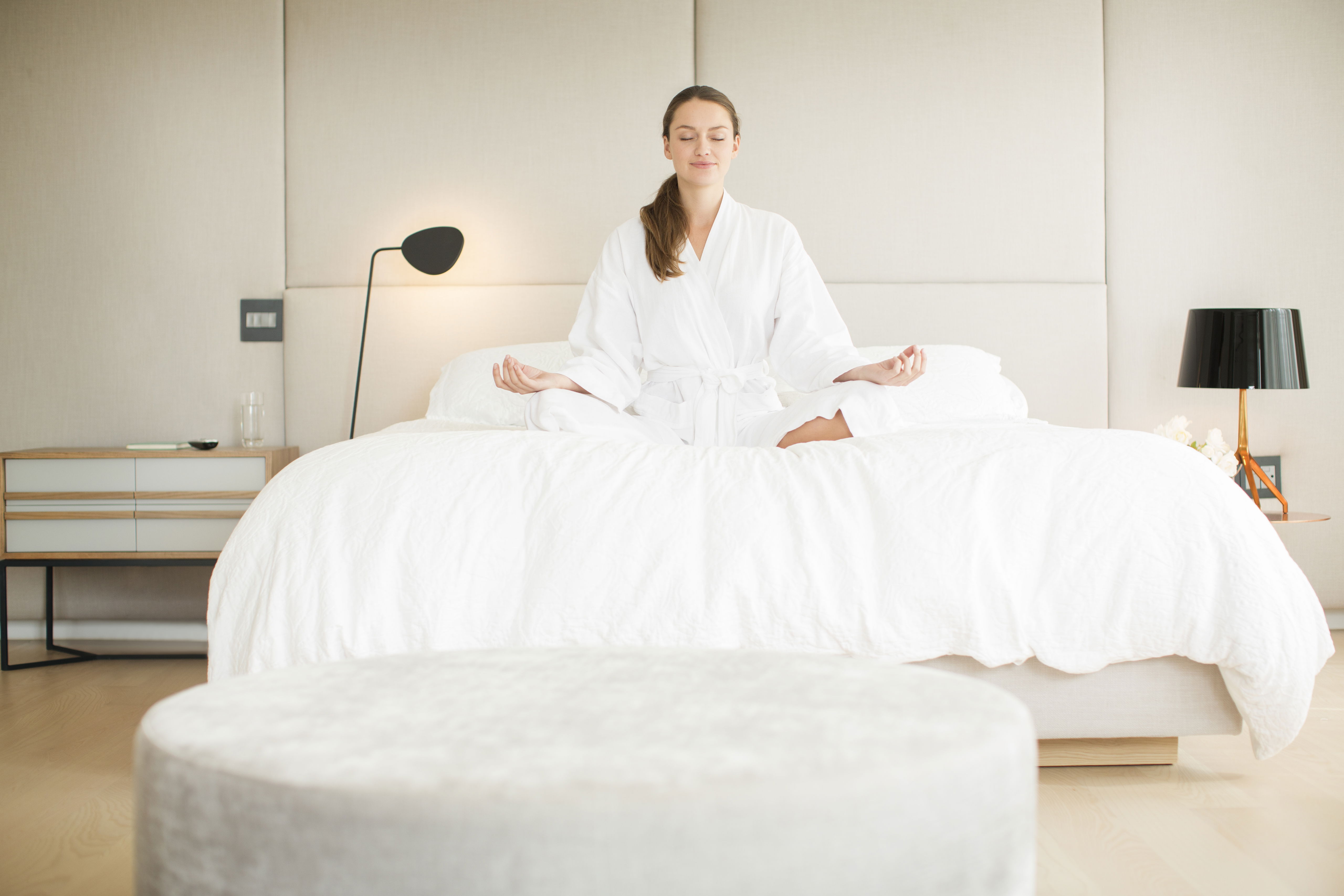 Jeune femme, assise sur son lit, en position de méditation.