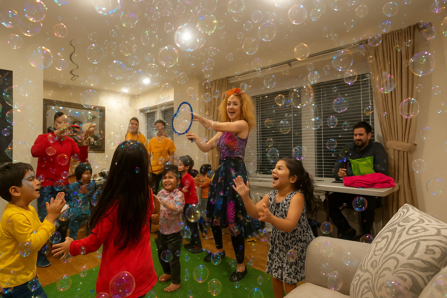 Kids enjoying an indoor bubble show in Toronto — an entertainer creating giant bubbles while children laugh, pop bubbles, and parents take pictures.