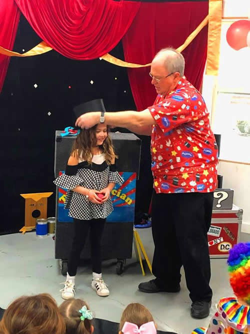 Young girl helping the magician on stage during an interactive daycare magic show in Toronto