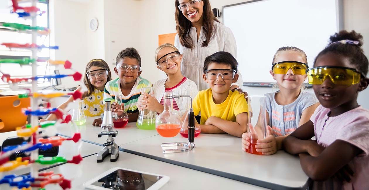 Group of children wearing safety goggles and smiling with science beakers during a daycare and school science show in Toronto
