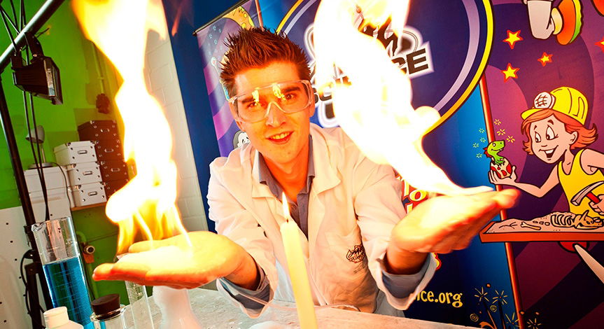 Science show performer demonstrating a controlled fire experiment during a kids science show