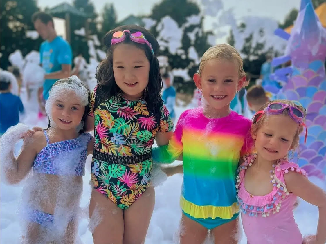 Group of smiling children standing together covered in soft foam during a daycare foam party in Toronto
