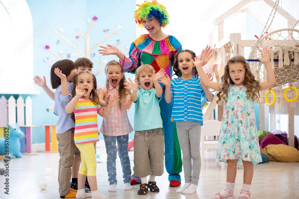 Clown entertainer posing with a group of smiling children during a daycare party in Toronto