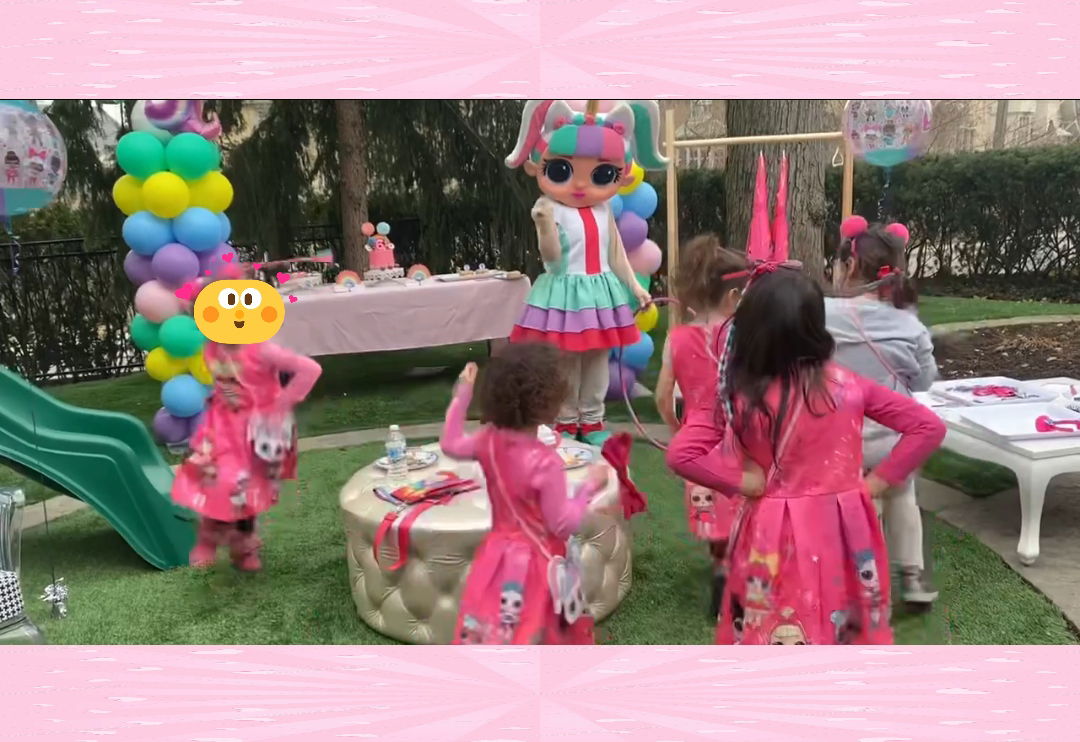 Kids dancing and playing outdoors with a colorful party character at a children’s birthday celebration, with balloons, decorations, and activity tables in the background.