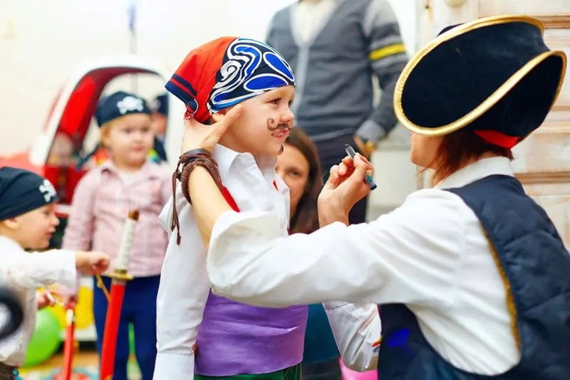 Pirate entertainer helping a child with light face painting during a daycare pirate entertainment program in Toronto