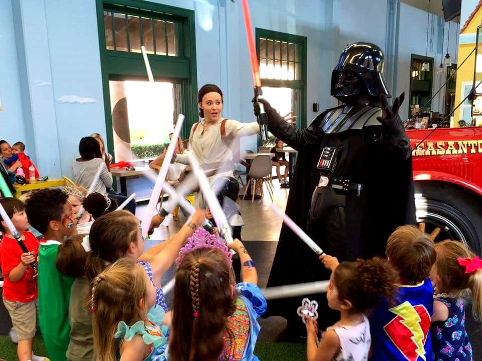 Children taking part in a themed lightsaber training activity with party characters at a kids event