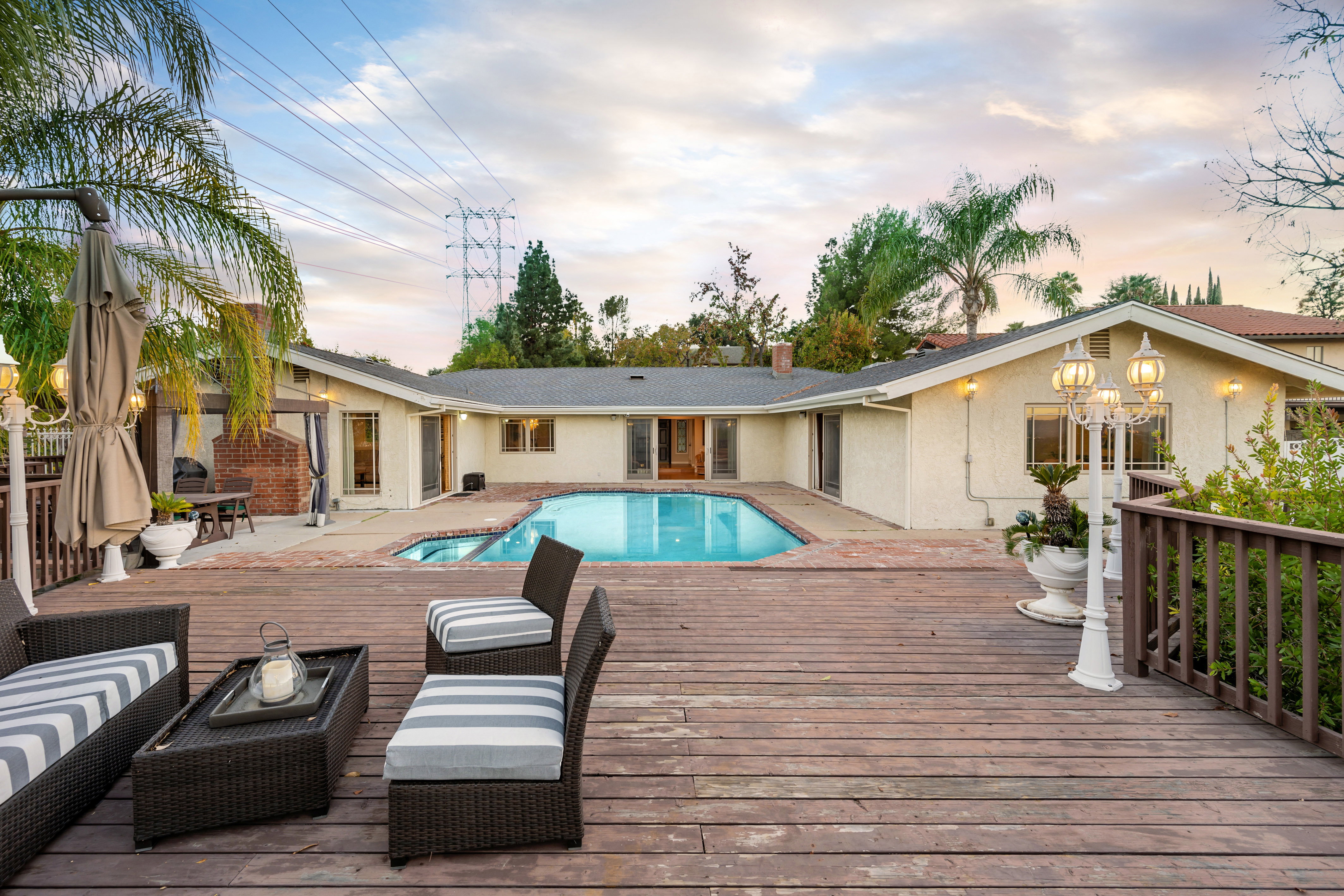 A spacious Los Angeles backyard with pool, wood patio, palm trees and blue skies.