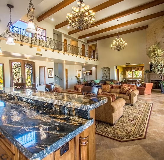 The main community gathering area at The Summit Sanctuary in Scottsdale, AZ. Showcasing multiple plush brown leather couches just outside of a large luxury kitchen and nook area. With plush coffee table and a large entertainment area equipped with sound system and fine decor.