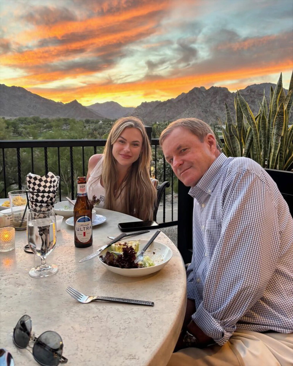 Devin Doyle dining with a family member outdoors as sunset colors fill the mountain sky