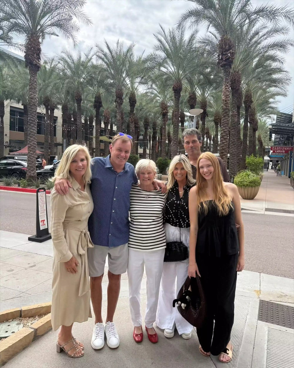 Devin Doyle standing beside family and friends on a sidewalk with palm trees behind