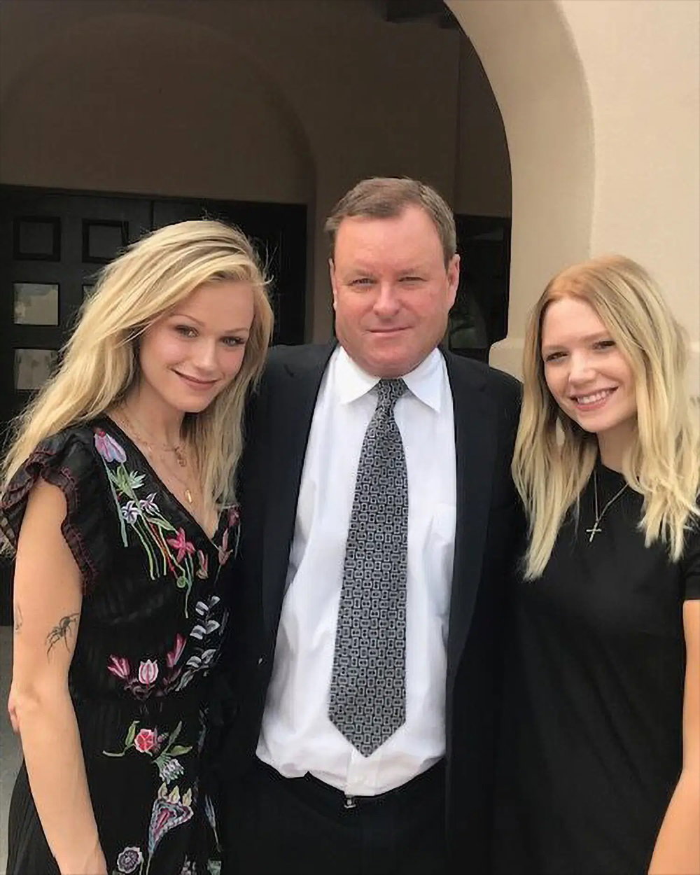 Devin Doyle posing with two family members outside while wearing a dark suit and patterned tie