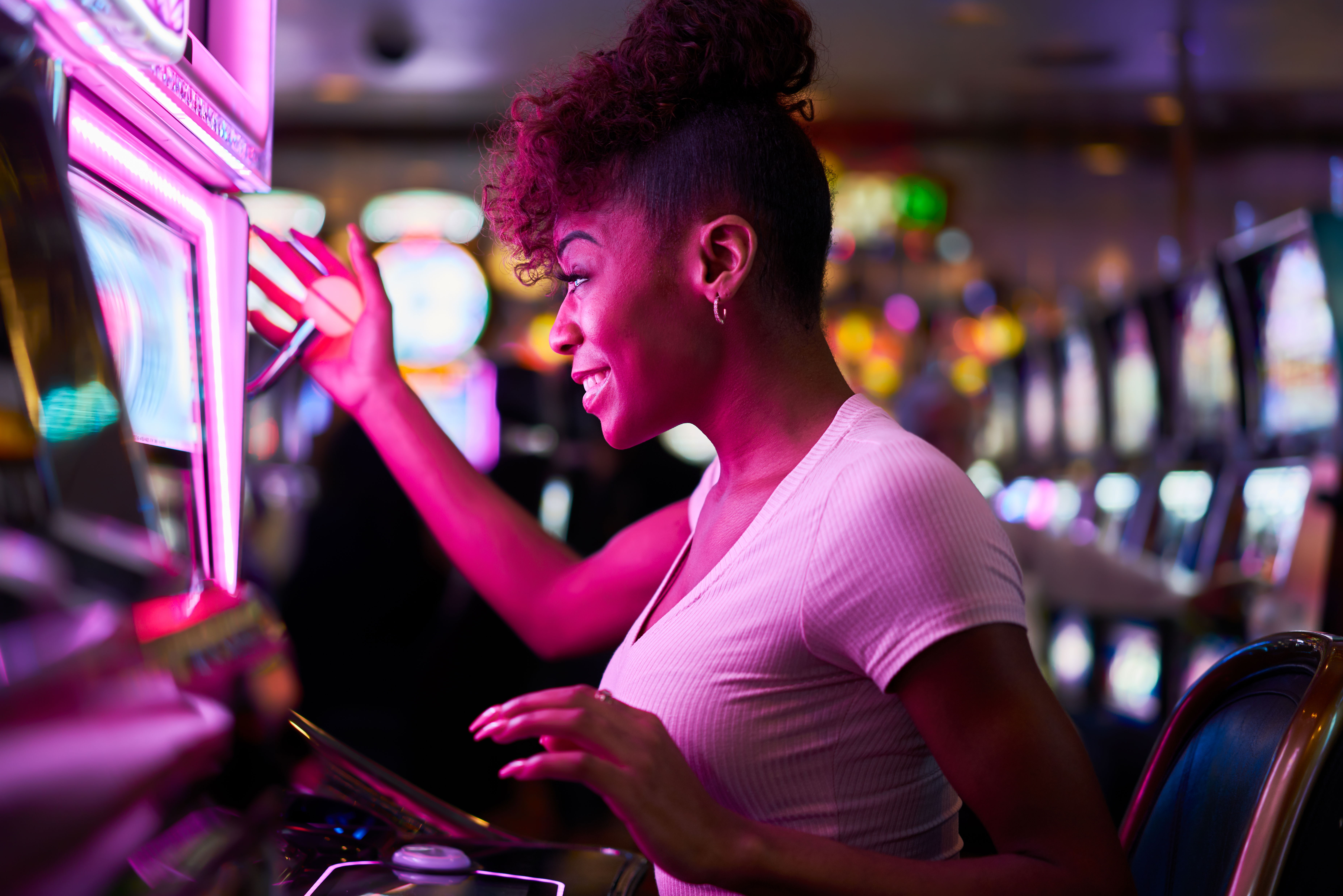 Image of a gorgeous perky African lady playing Slots on a casino floor.