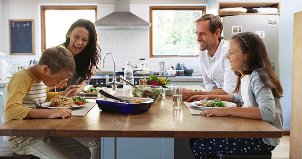 Two children and their parents laughing in the kitchen