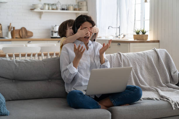 Parent working at a laptop while a child plays nearby